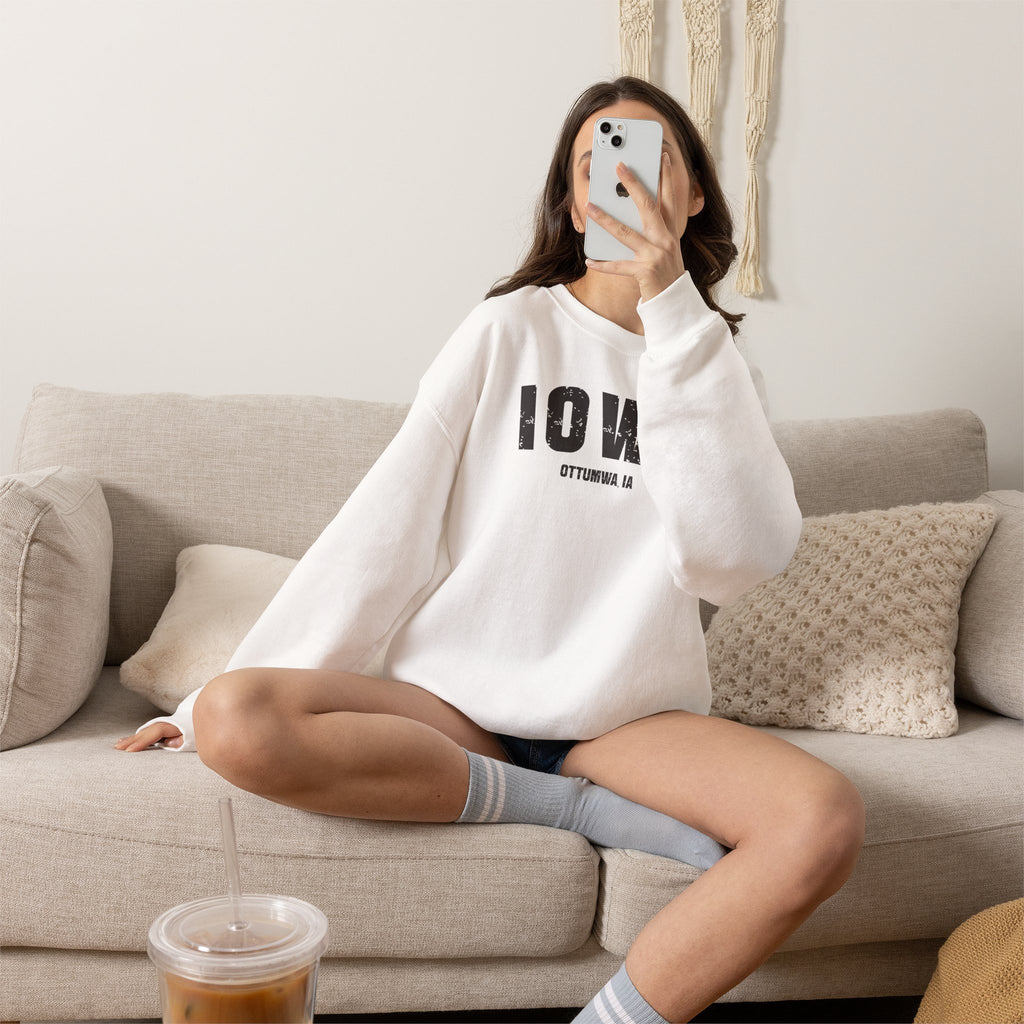 Woman relaxing on a sofa in the white Iowa sweatshirt printed IOWA over OTTUMWA IA