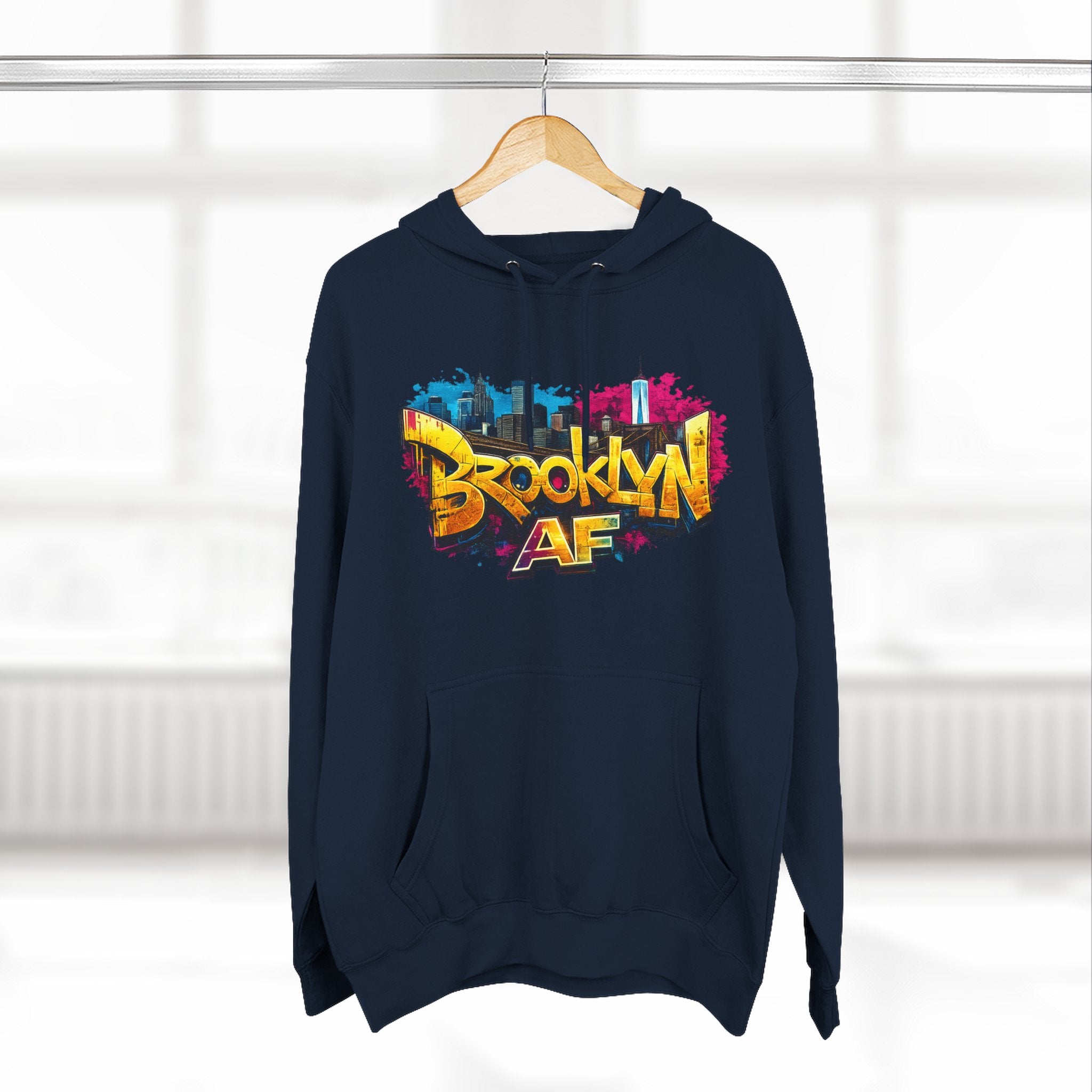Navy hoodie hanging on a wooden hanger, showing the colorful graffiti-style Brooklyn AF skyline print.