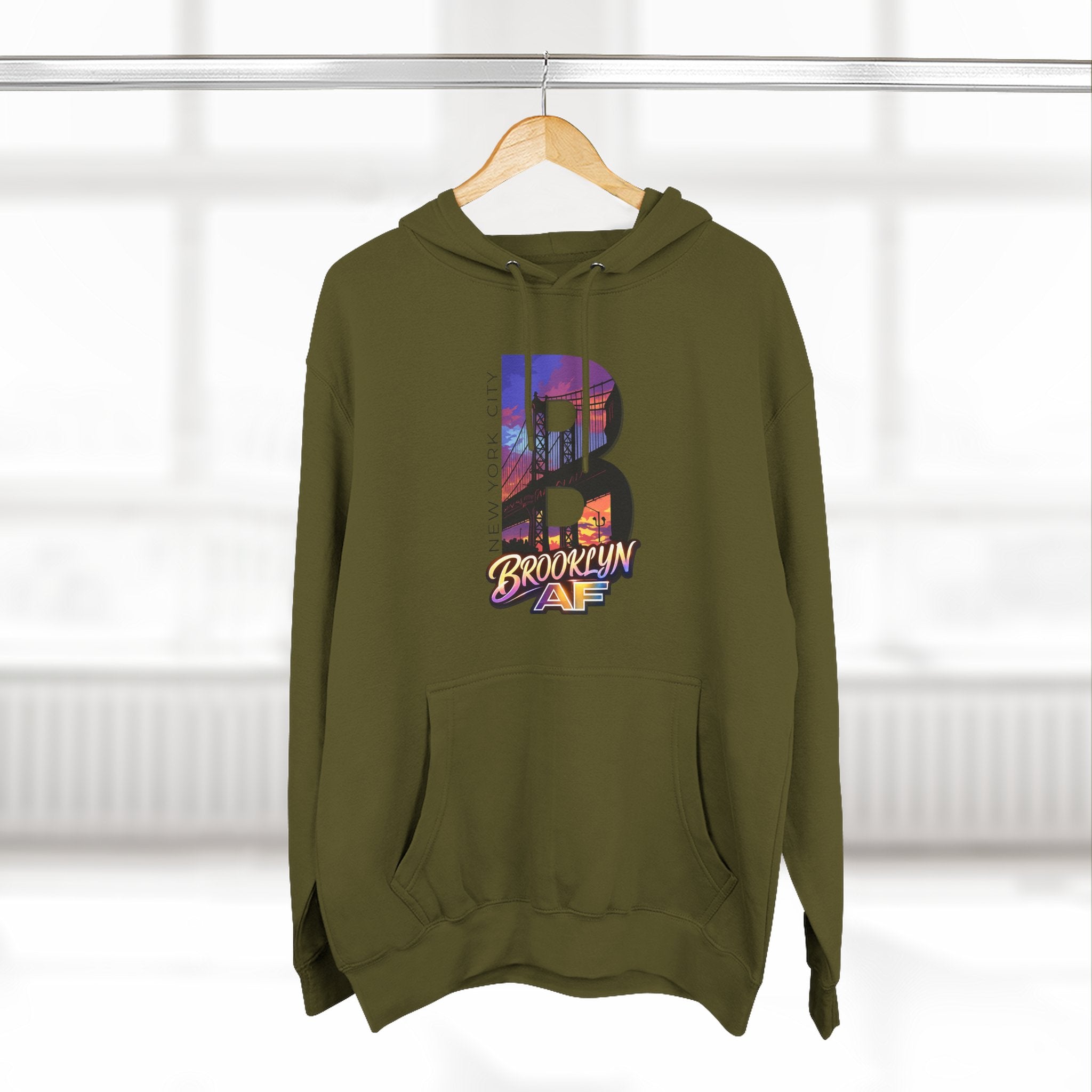 Army green hoodie hanging on a wooden hanger, bold B with a Brooklyn Bridge sunset skyline graphic and Brooklyn AF logo.