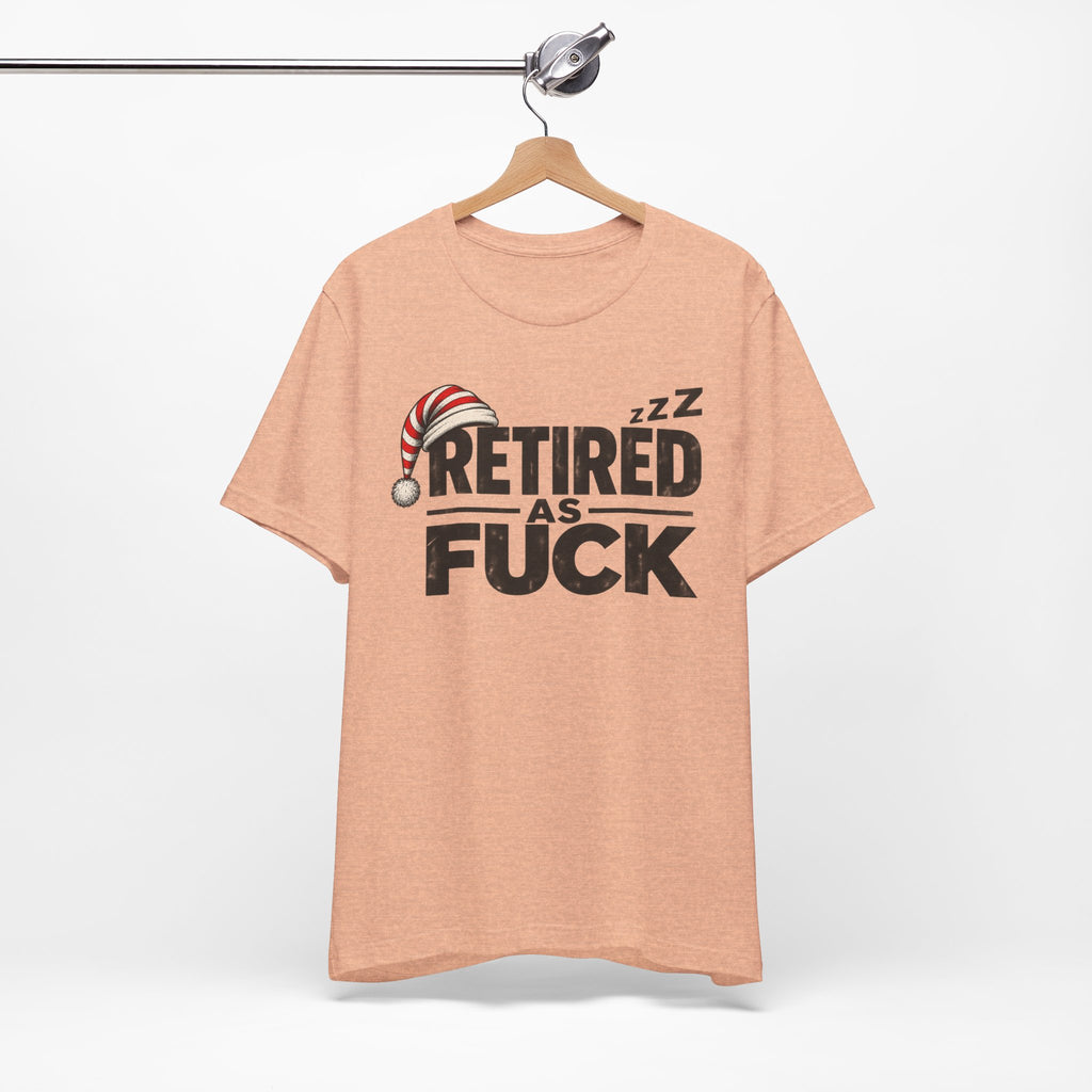 Heather Peach Retired As Fuck T-shirt hanging on a wooden hanger against a plain wall