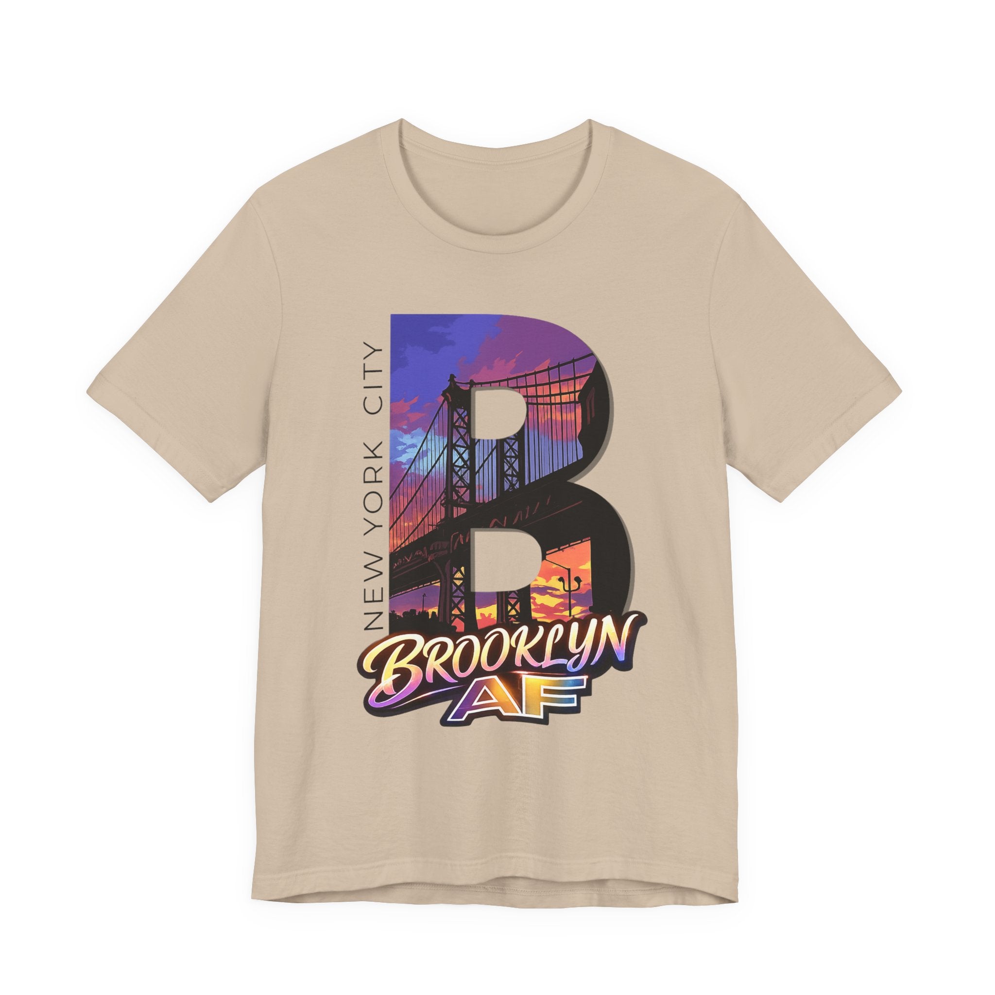 Sand-colored t-shirt, flat lay, with a bold oversized "B" featuring a Brooklyn Bridge sunset skyline graphic.