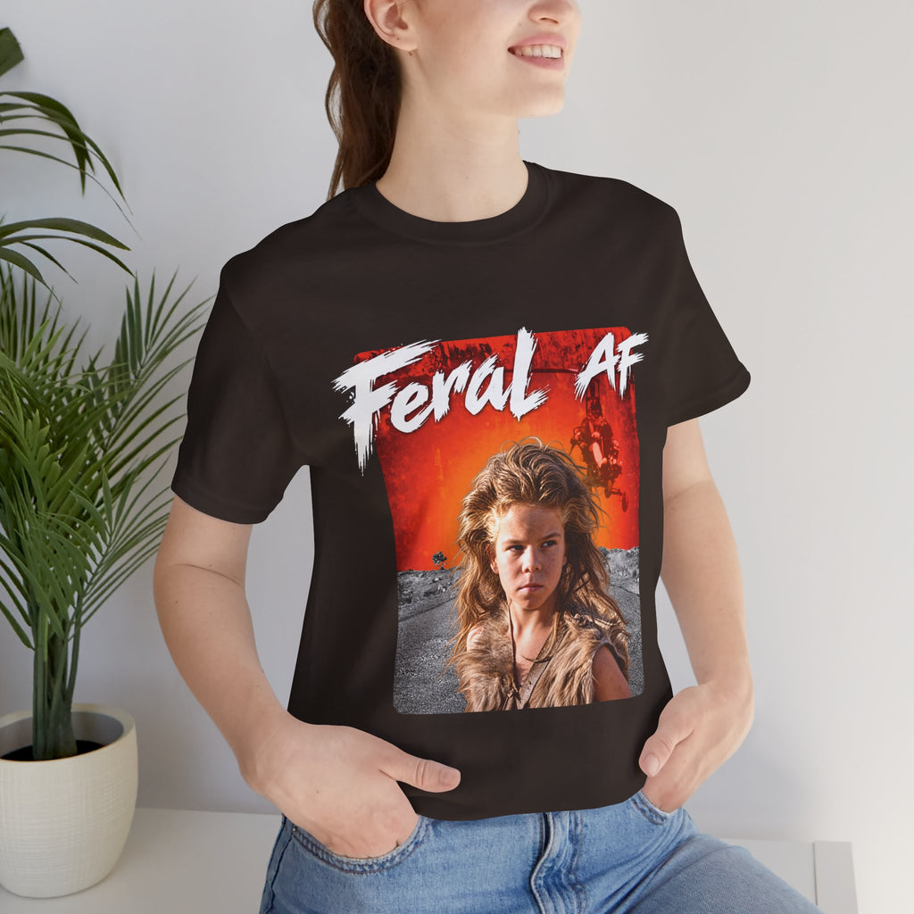 Woman wearing the Brown Feral AF T-shirt indoors beside a potted palm, front print at chest height