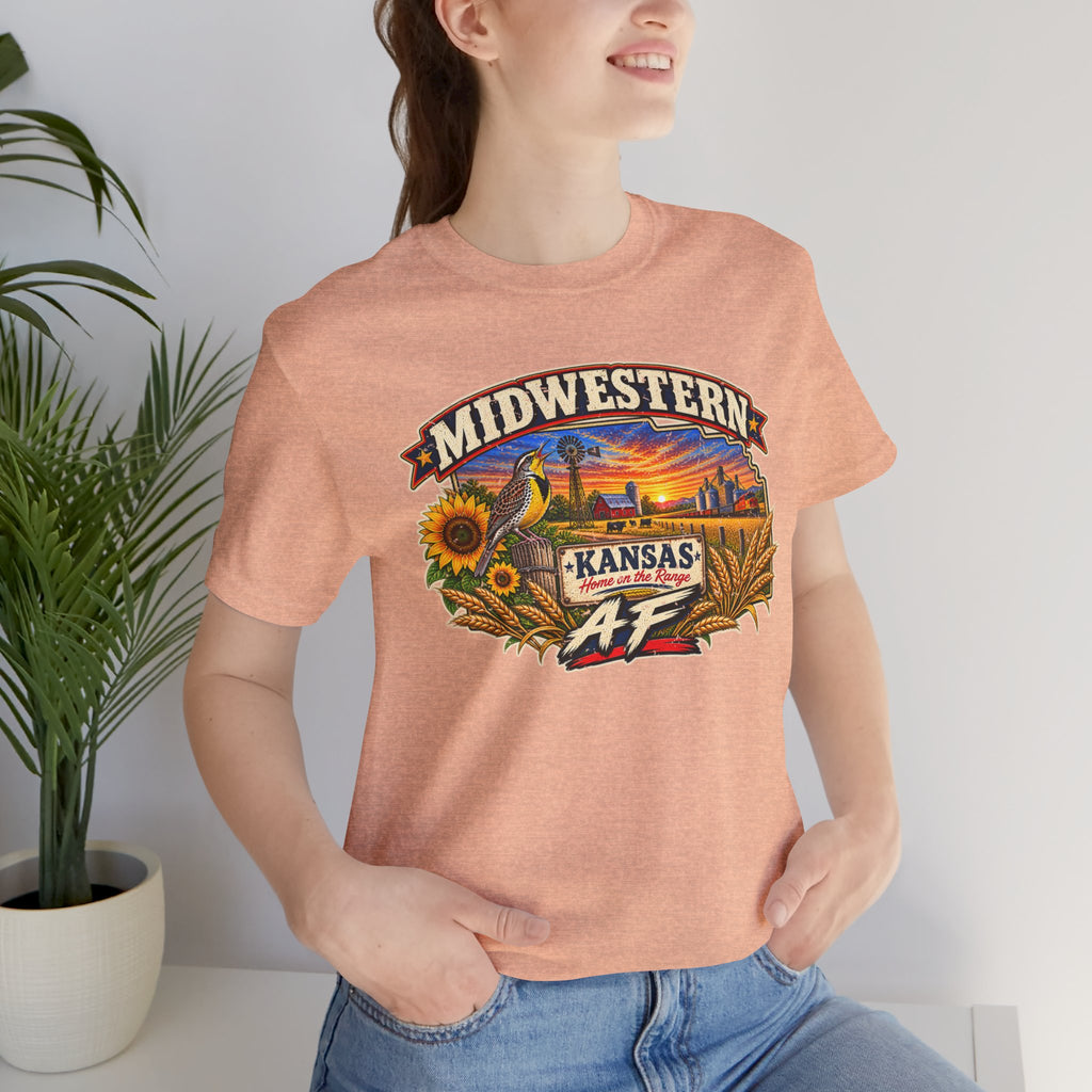Close crop of the heather peach Kansas AF tee worn indoors beside a plant