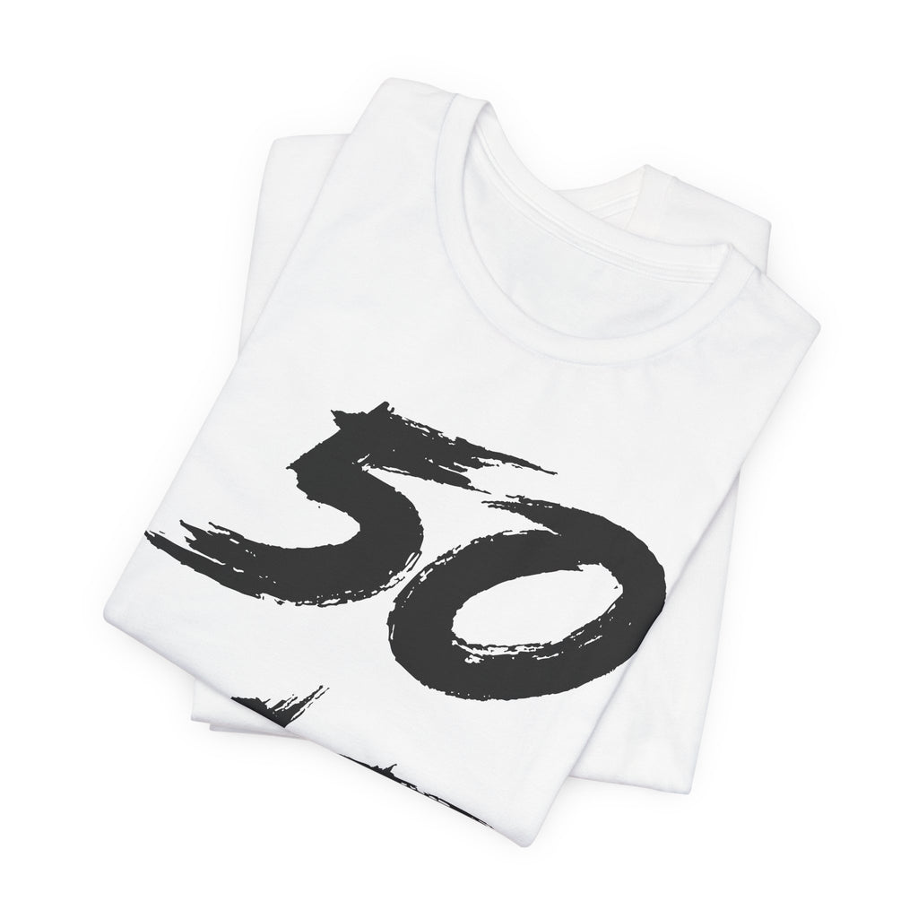 Folded white birthday tees stacked, the black 50 print showing on the top fold