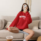 Woman relaxing on a sofa in the red personalized Missouri sweatshirt with varsity MISSOURI lettering