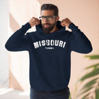 Bearded man pulling up the hood of the navy Missouri hoodie printed MISSOURI over THE OZARKS