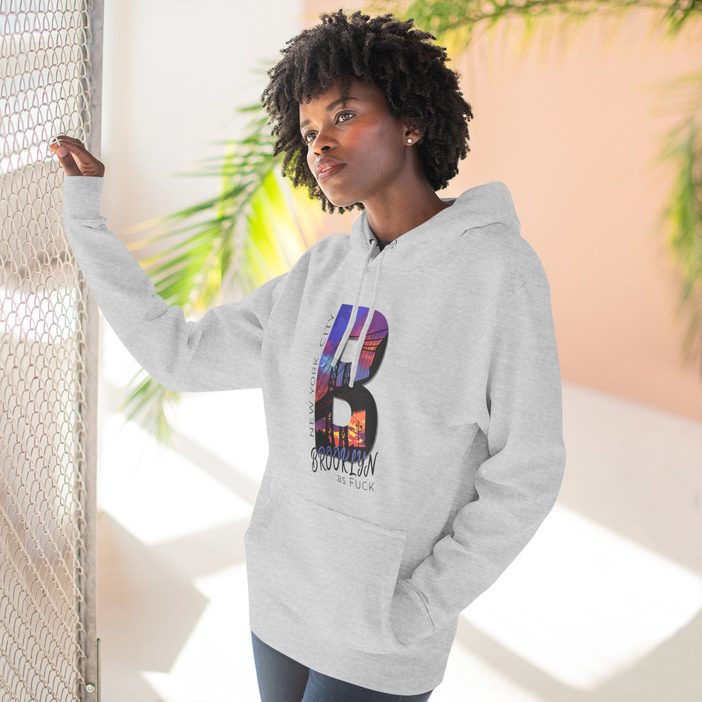Heather grey hoodie worn by a model outdoors near a fence, showing the 'B' Brooklyn skyline graphic and 'As Fuck' text.