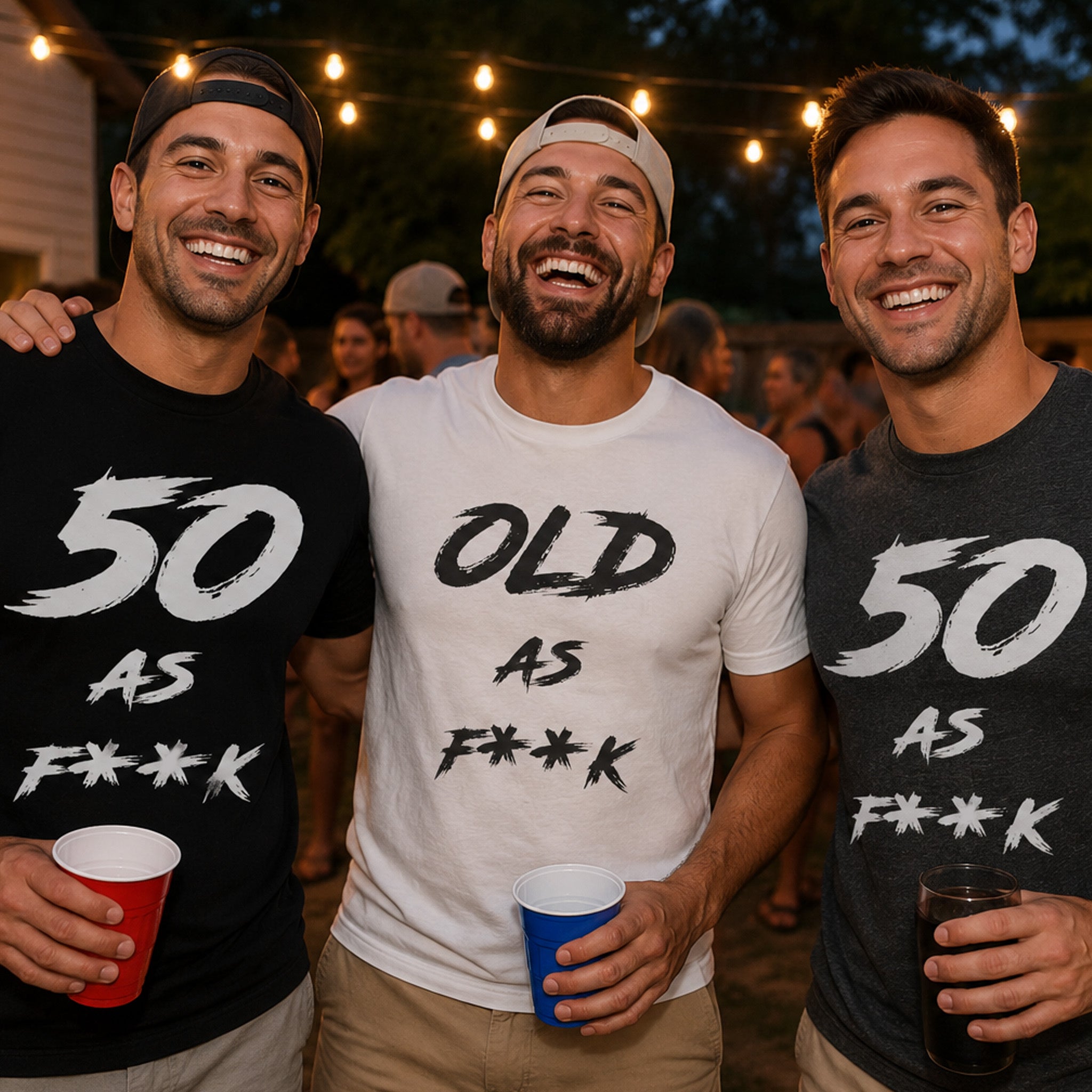 Three men at an outdoor party under string lights in black, white and dark grey 50 AS F**K and OLD AS F**K tees