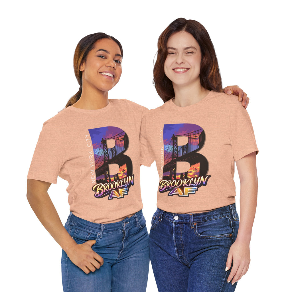 Heather peach t-shirts worn by two female models, front view, each with a purple-orange Brooklyn Bridge sunset B graphic.