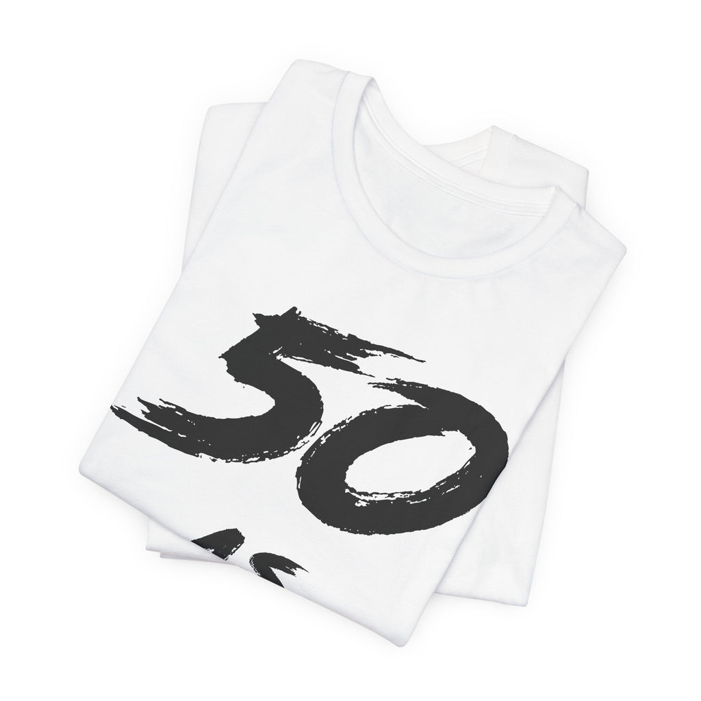 Folded white birthday tees stacked, the black 50 print showing on the top fold