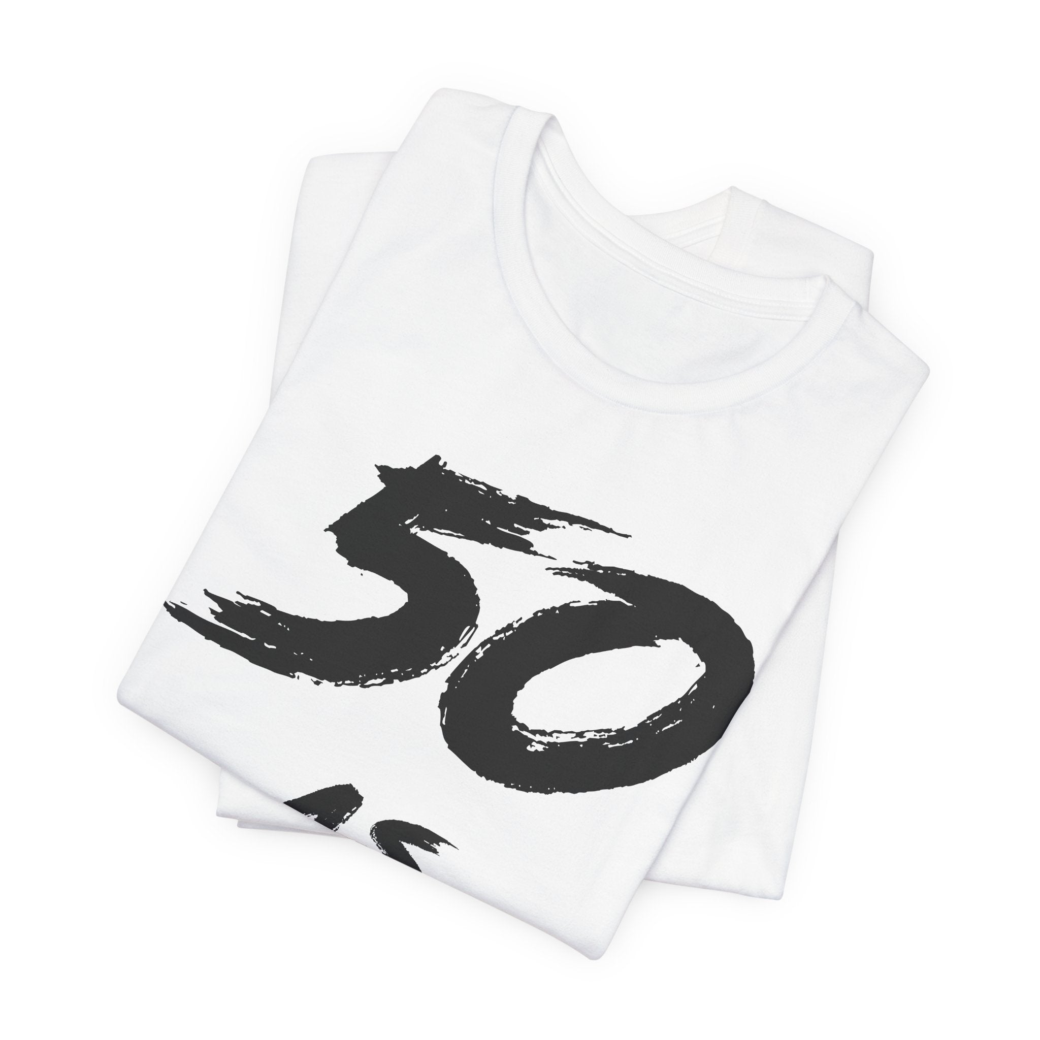 Folded white birthday tees stacked, the black 50 print showing on the top fold