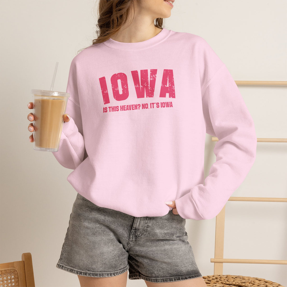 Woman in the light pink Iowa crewneck printed IS THIS HEAVEN? NO IT'S IOWA under varsity IOWA