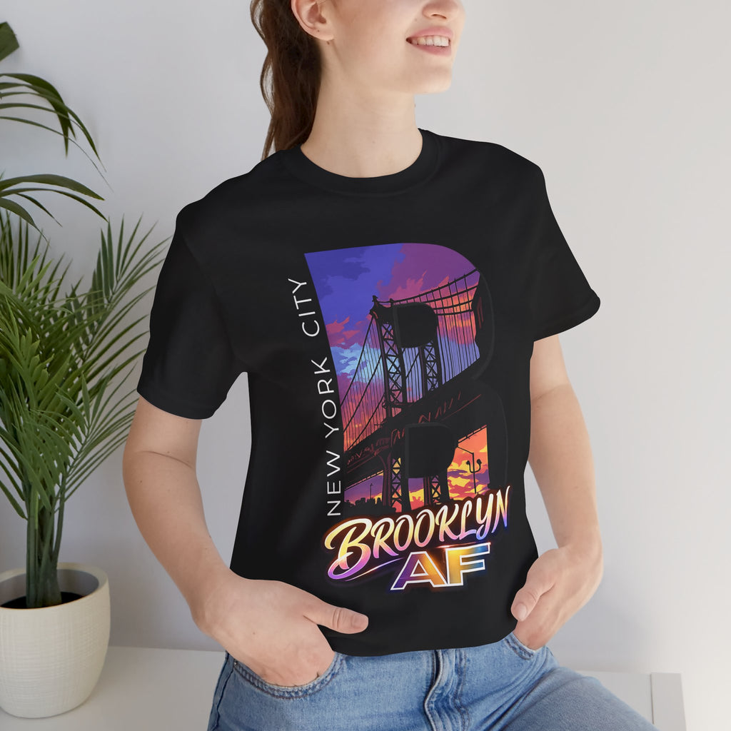 Black t-shirt worn by a female model near a potted plant, front view, purple-orange Brooklyn Bridge sunset B graphic.