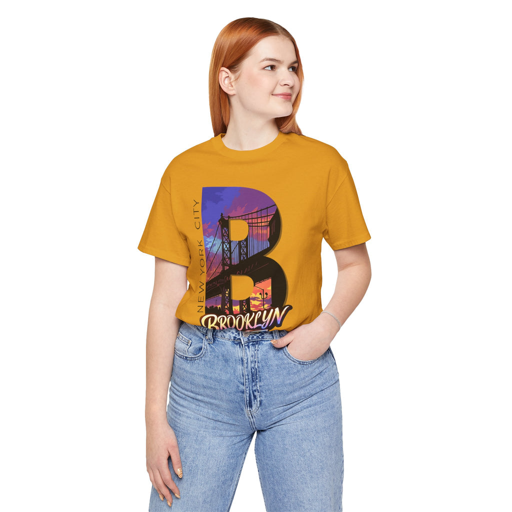 Mustard tee worn by a female model, front view, with the oversized "B" Brooklyn Bridge sunset skyline graphic.