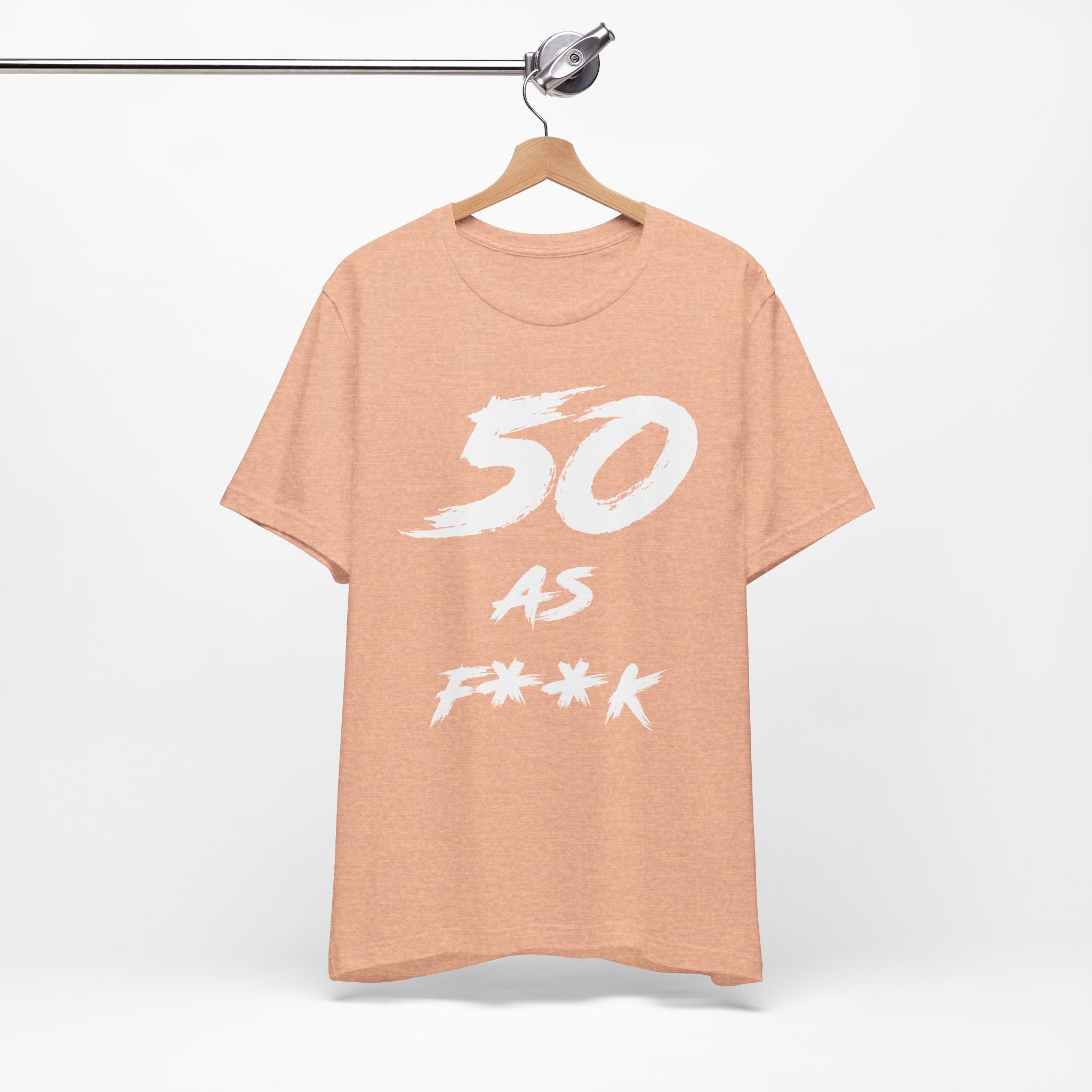 Heather Peach birthday t-shirt on a wooden hanger showing the white 50 AS F**K print
