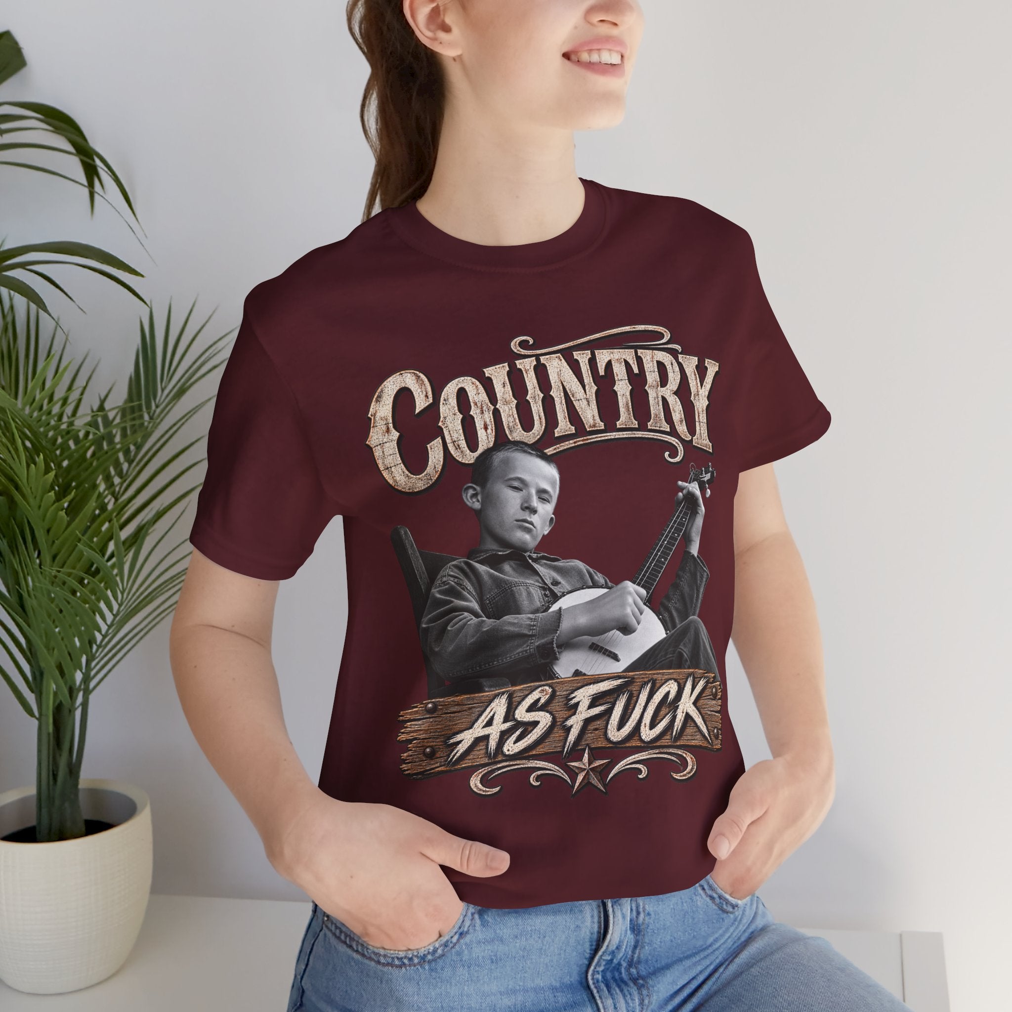 Woman by a potted plant in the Maroon Country As Fuck tee