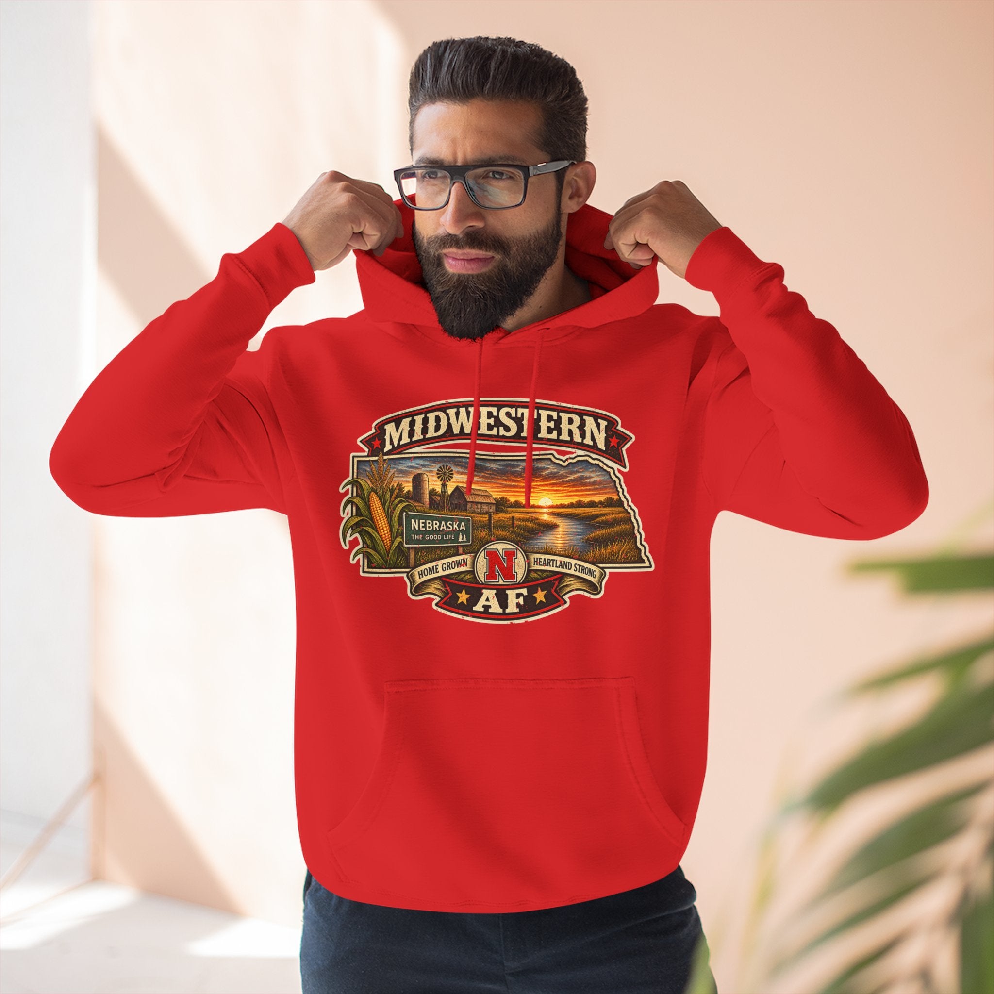 Bearded man in the red Nebraska hoodie against a warm stucco wall