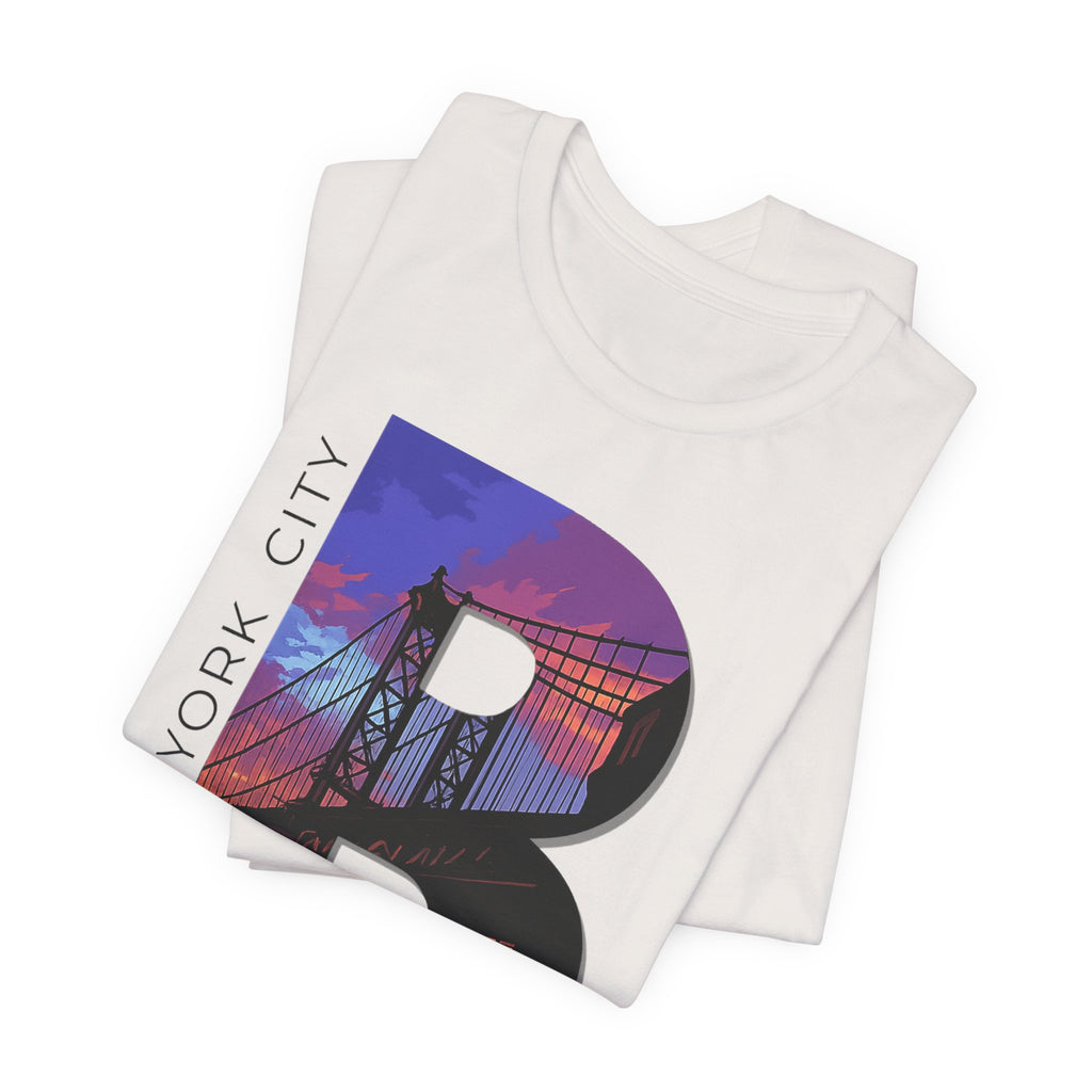 Folded stack of White tees, close-up of the "B" Brooklyn Bridge sunset skyline chest print and "New York City" text.