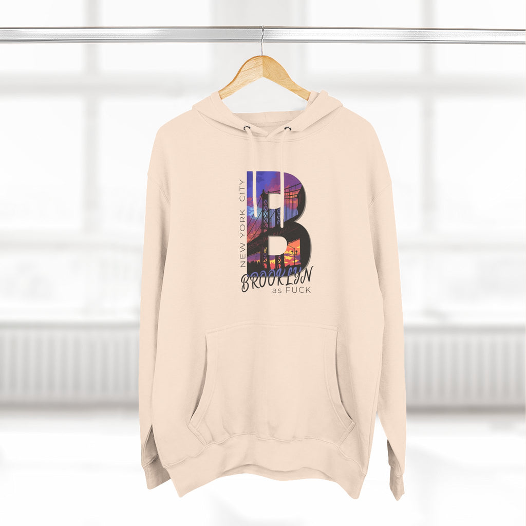 Oatmeal heather hoodie on a wooden hanger, front view, featuring the 'B' Brooklyn skyline graphic and 'As Fuck' text.