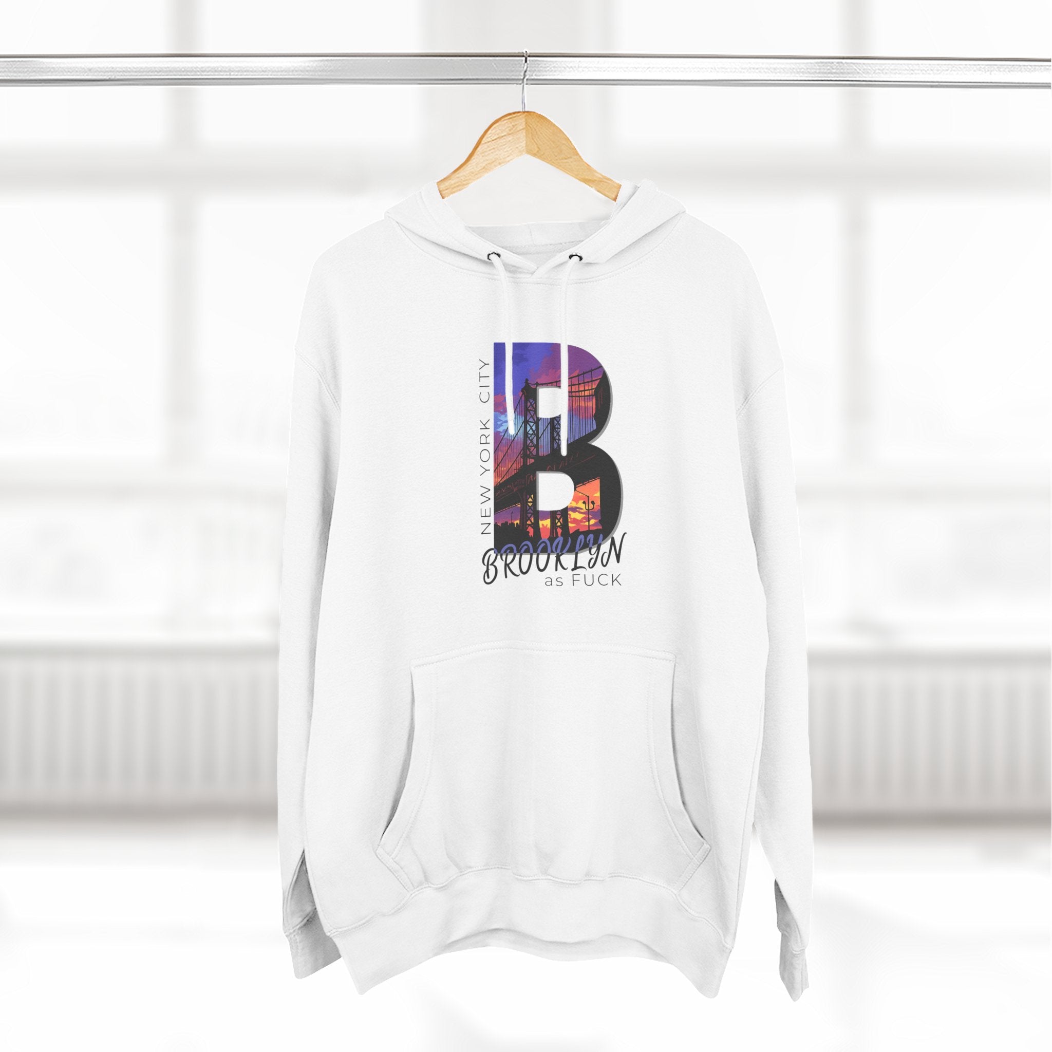 White hoodie on a wooden hanger, front view, featuring the 'B' Brooklyn skyline graphic and 'As Fuck' text.