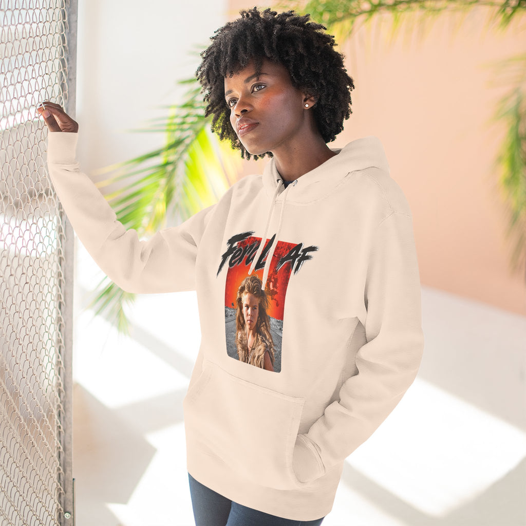 Woman wearing the Pale Pink Feral AF hoodie by a sunlit doorway, front graphic centred