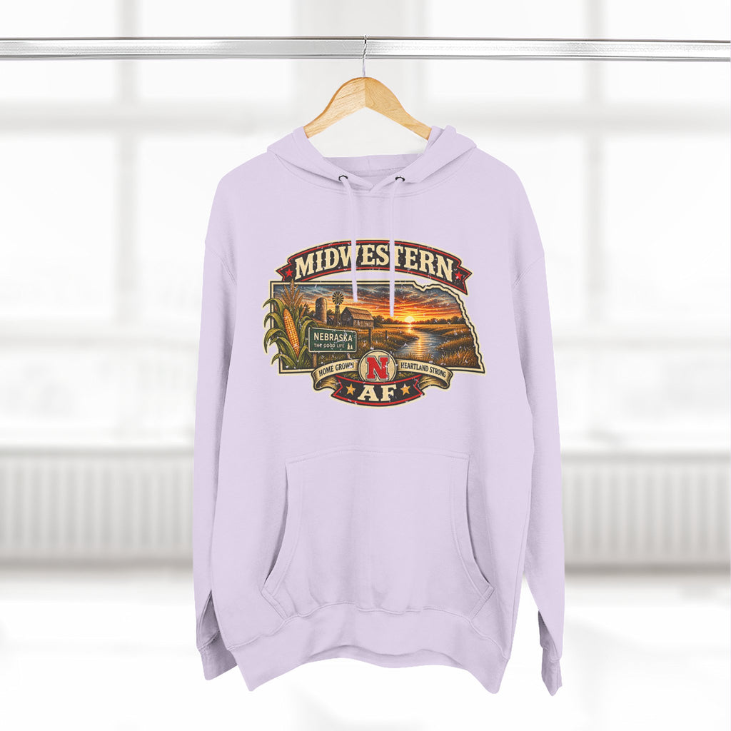 Lilac Nebraska hoodie hanging by a window with the Cornhusker State sunset badge on the chest
