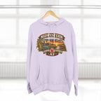 Lilac Nebraska hoodie hanging by a window with the Cornhusker State sunset badge on the chest