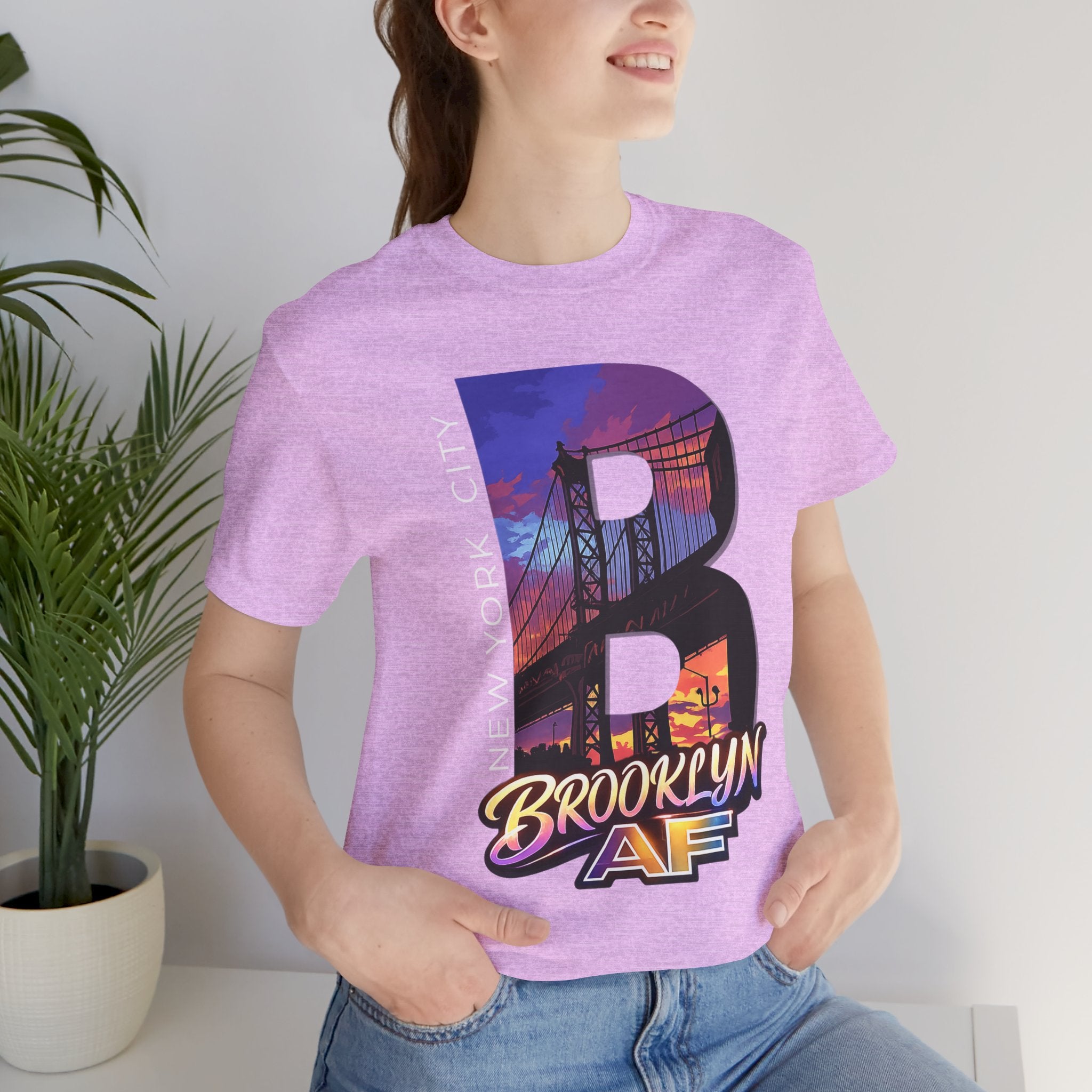 Heather prism lilac tee worn by a model, close-up front view of the B with a purple-orange Brooklyn Bridge sunset graphic.