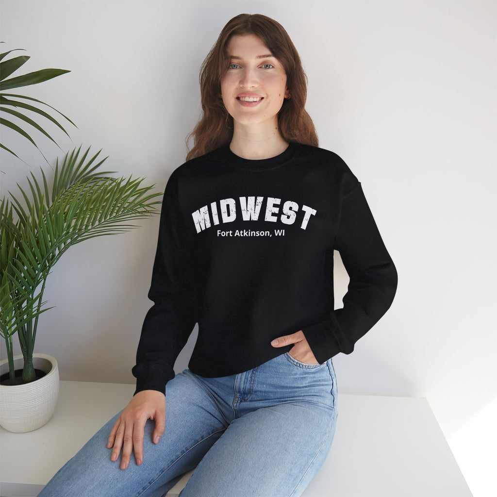 Woman seated beside a houseplant in the Black custom Midwest crewneck and jeans