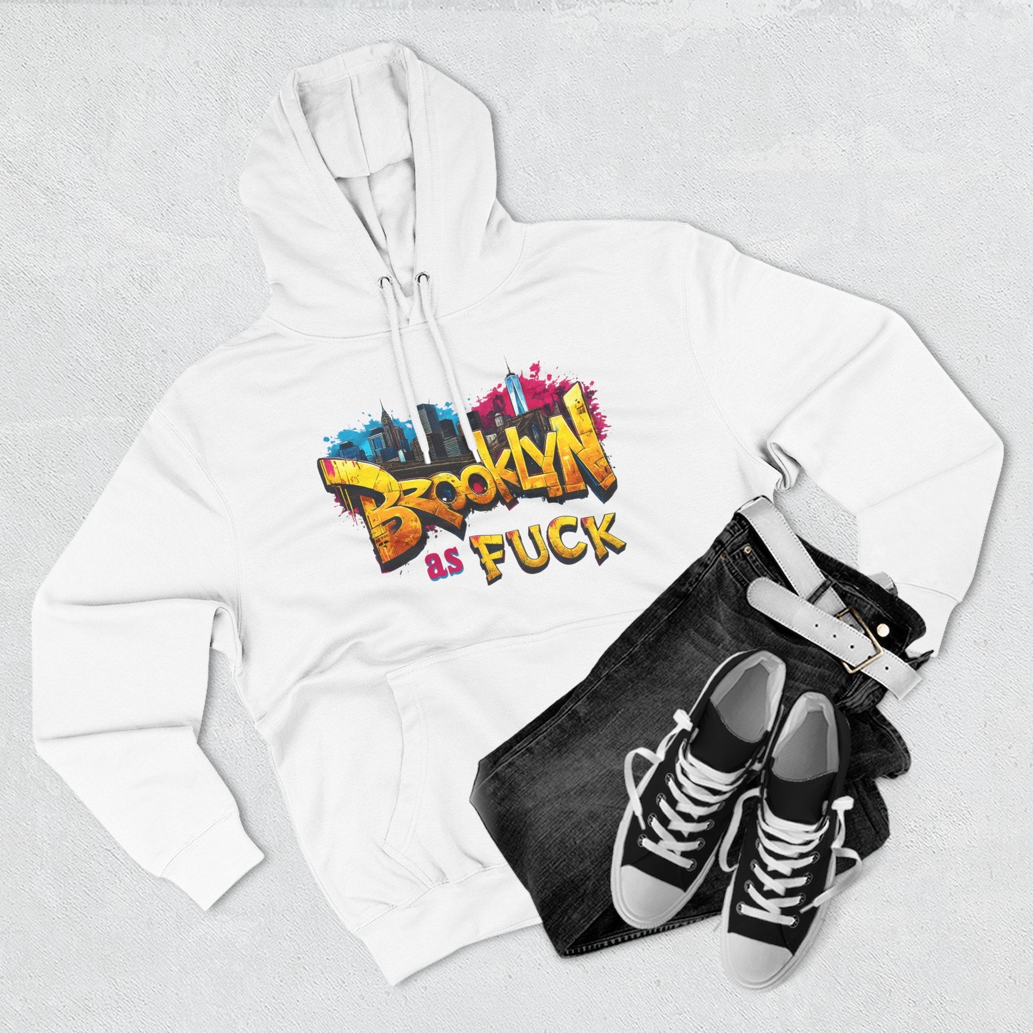 White hoodie styled flat lay with jeans, belt, and sneakers, graffiti Brooklyn As Fuck NYC skyline print.