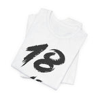 Folded white birthday tees stacked, the black 18 showing on the top fold