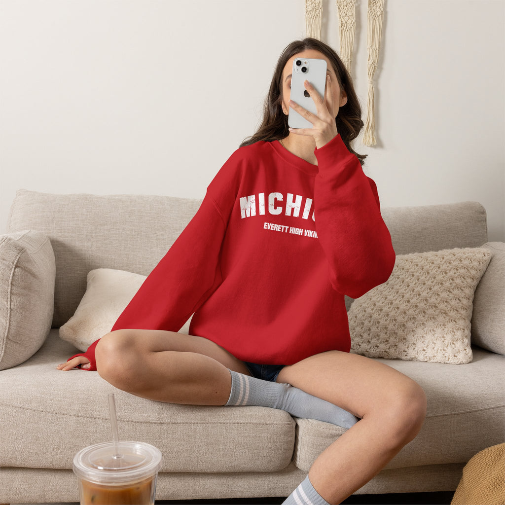 Woman on a sofa in the red personalized Michigan sweatshirt with white varsity MICHIGAN lettering