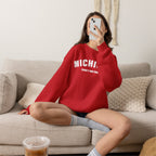 Woman on a sofa in the red personalized Michigan sweatshirt with white varsity MICHIGAN lettering