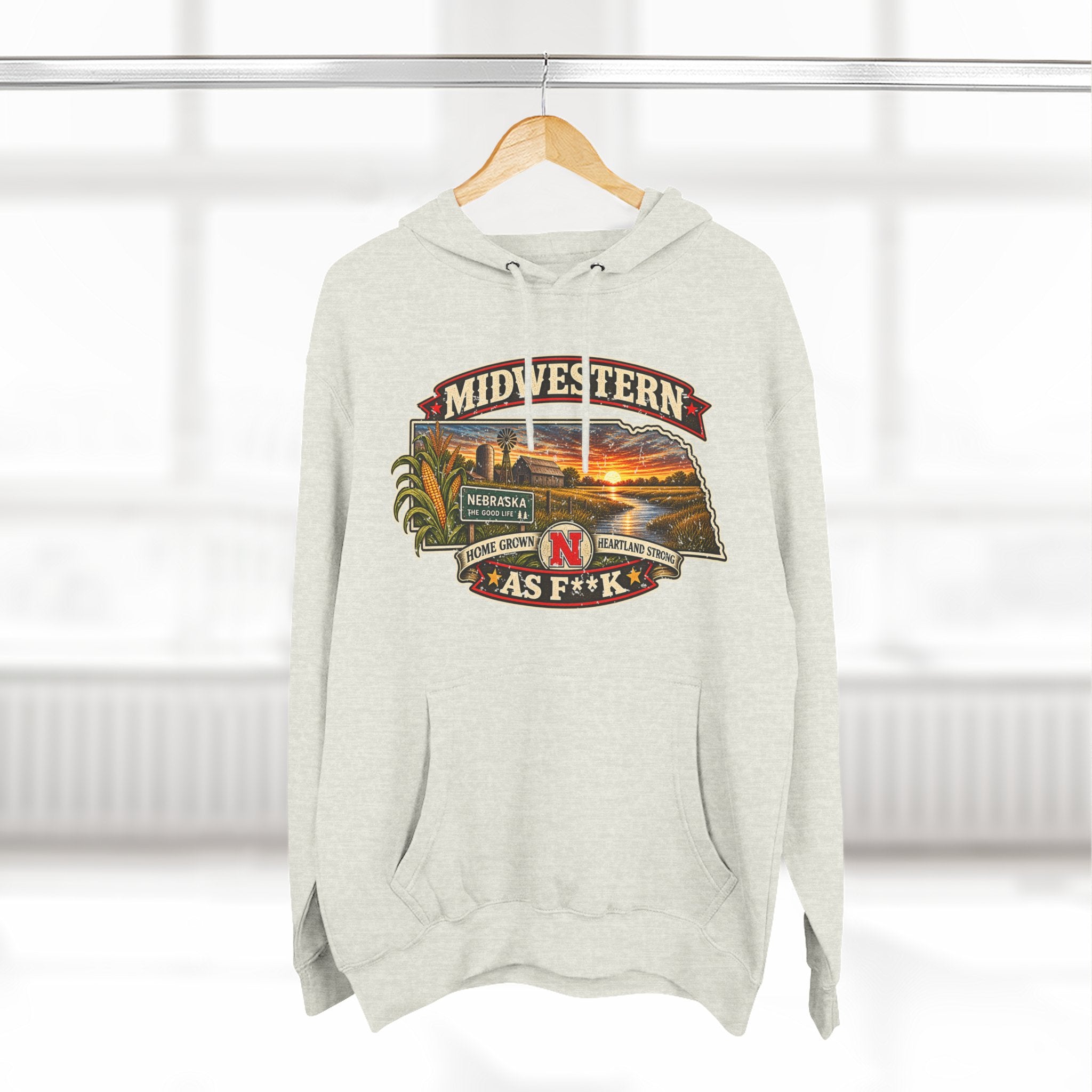 Oatmeal heather Nebraska As F**K hoodie hanging by a window, front print on show