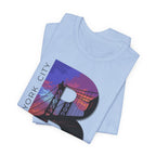 Light blue t-shirt folded in a stack, close-up of the oversized 'B' with Brooklyn Bridge sunset skyline graphic