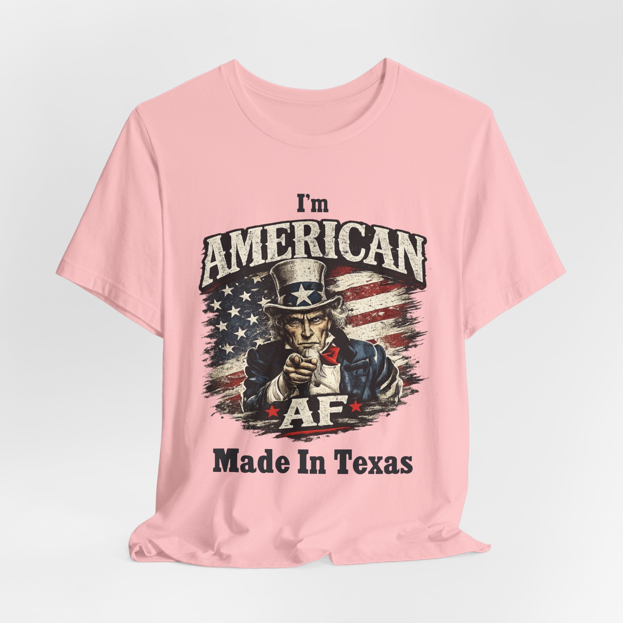 Pink tee laid flat with a relaxed drape, showing Uncle Sam graphic and 'Made In Texas' text