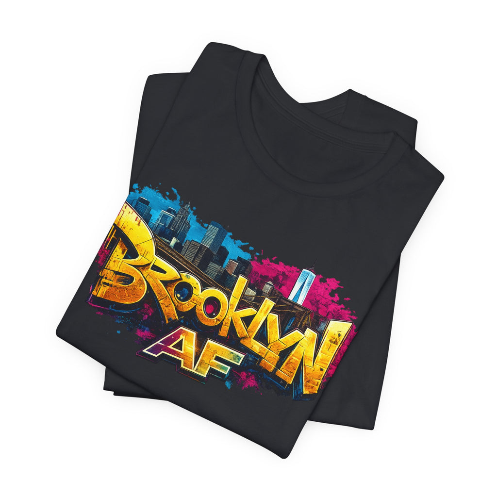 Black t-shirts folded in a stack, featuring graffiti-style Brooklyn AF lettering over a skyline paint-splash design.
