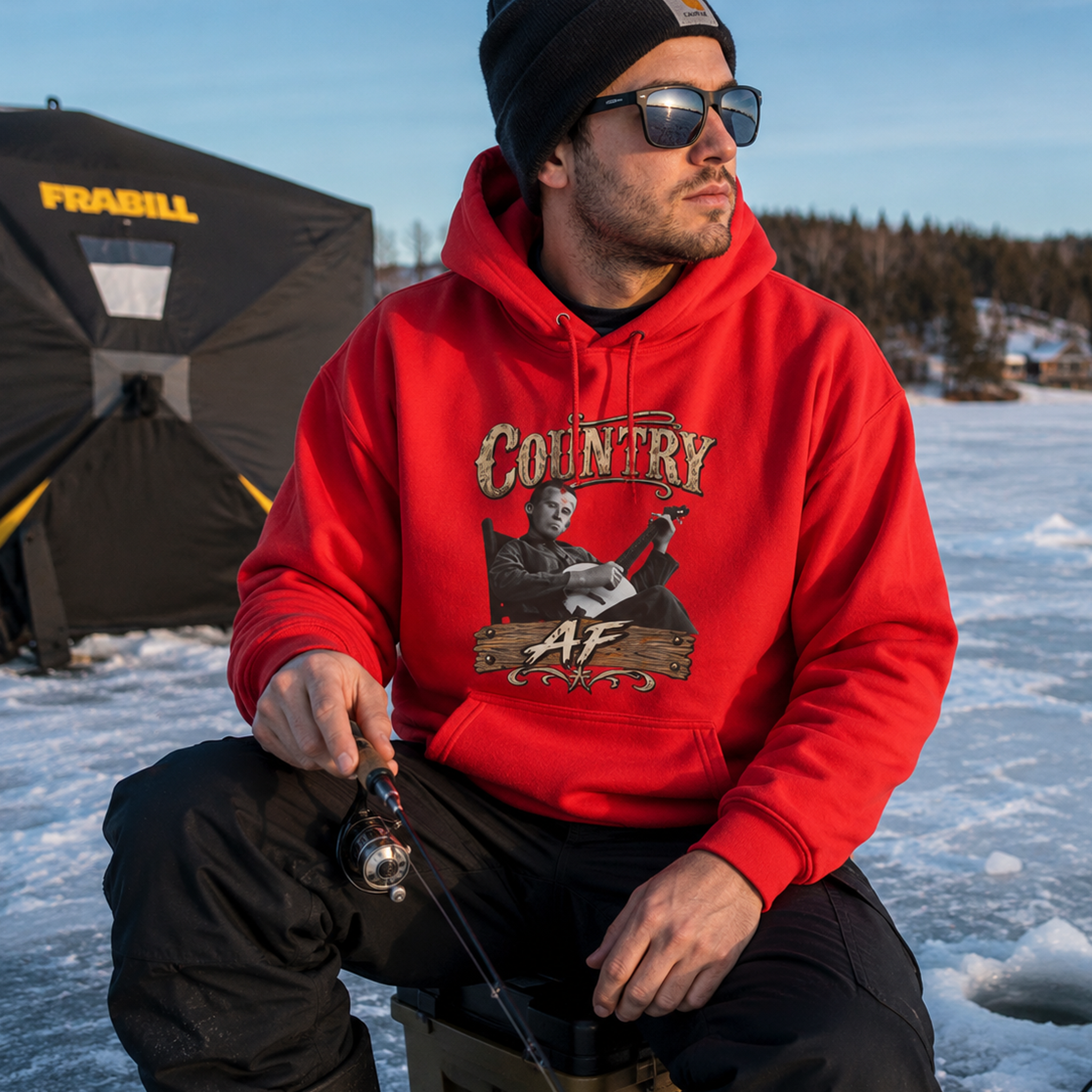 Man kneeling by an ice-fishing shelter in the Red Country AF hoodie