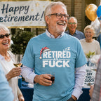Man in the Heather Aqua Retired As Fuck tee laughing at an outdoor retirement party under a Happy Retirement banner