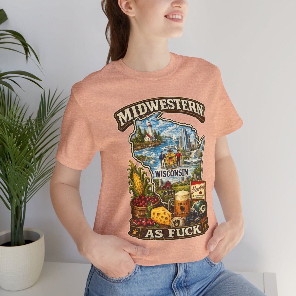 Woman beside a potted plant wearing the Heather Peach Wisconsin Midwestern As Fuck tee